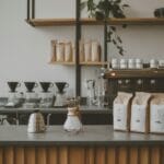 A photo of a modern specialty coffee shop with minimalist design, a pour-over station, and bags of single-origin coffee prominently displayed